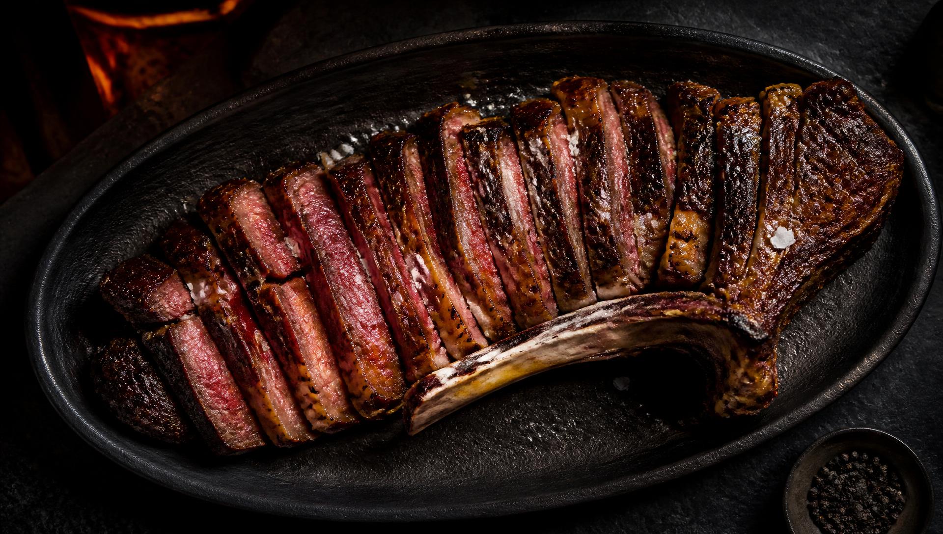 Aufgeschnittenes Steak auf einer großen Edelstahlplatte am Feuer